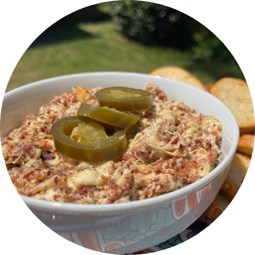 sausage jalapeno popper dip in a white bowl with toast