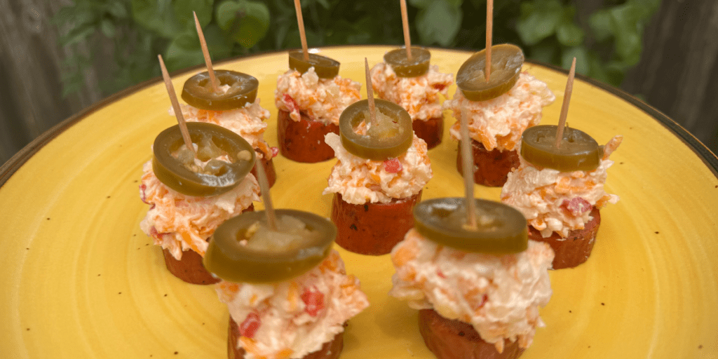 sausage pimento bites on a serving board with pickled jalapeños